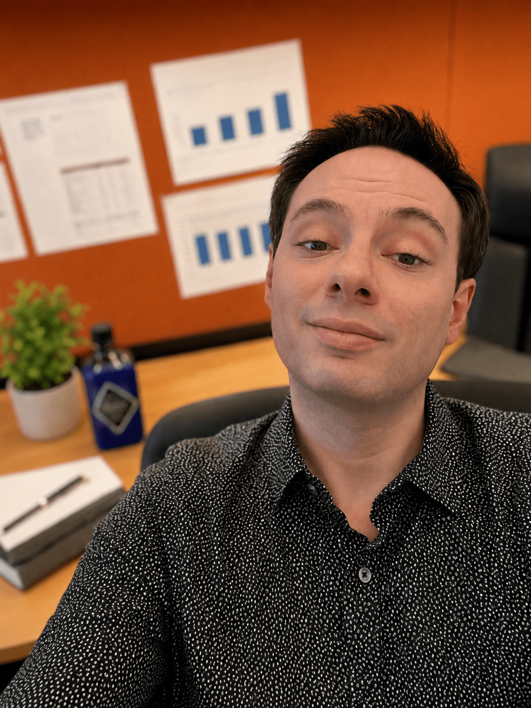 Patrick Diogenia working in an office with charts in the background